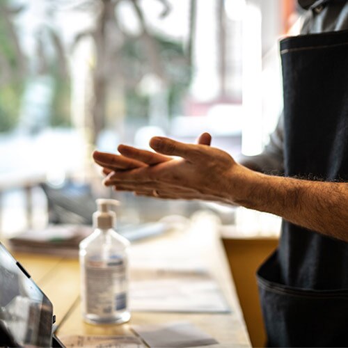 Man with apron using hand sanitizer